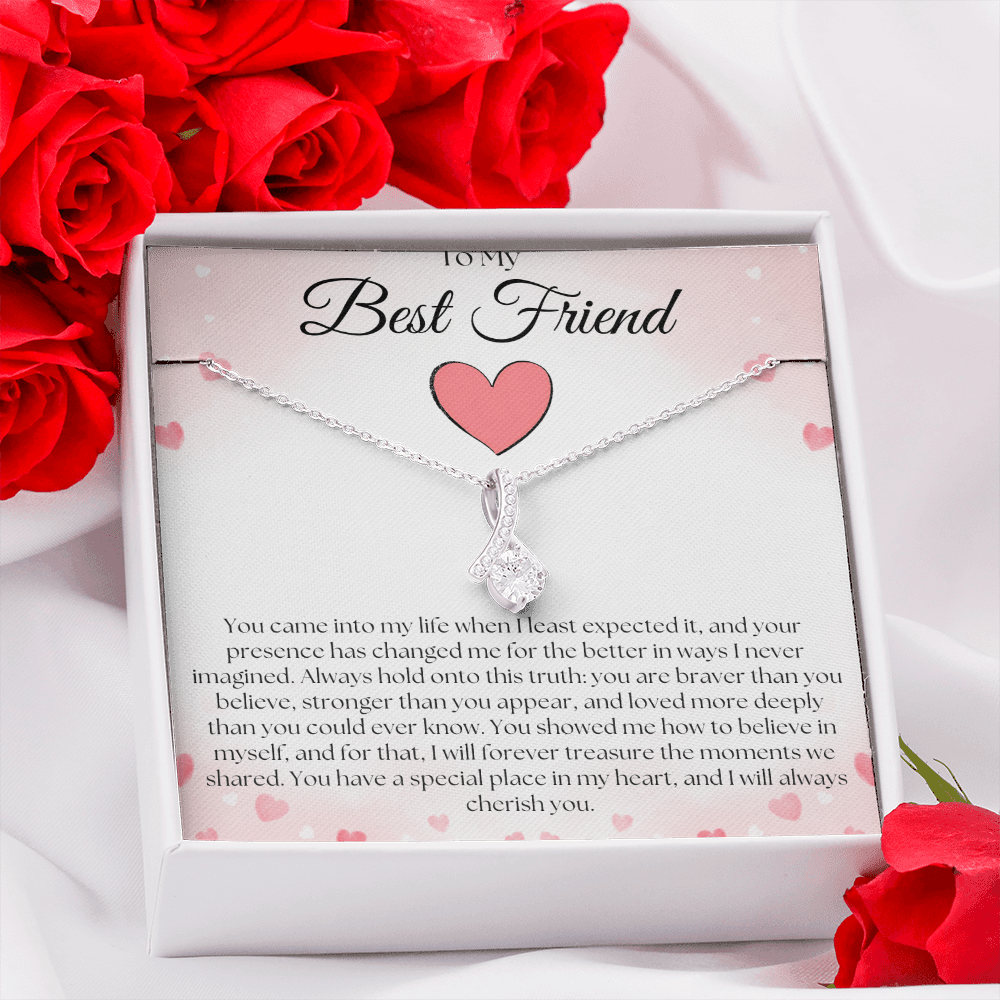 Silver-tone pendant necklace and pink-heart best-friend card in a white gift box surrounded by red roses.