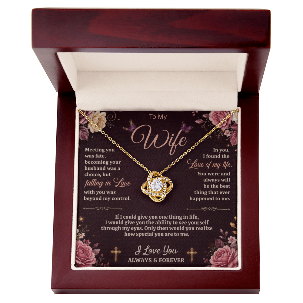 Gold-tone love-knot necklace and dark floral wife card in an open reddish-brown gift box on white.