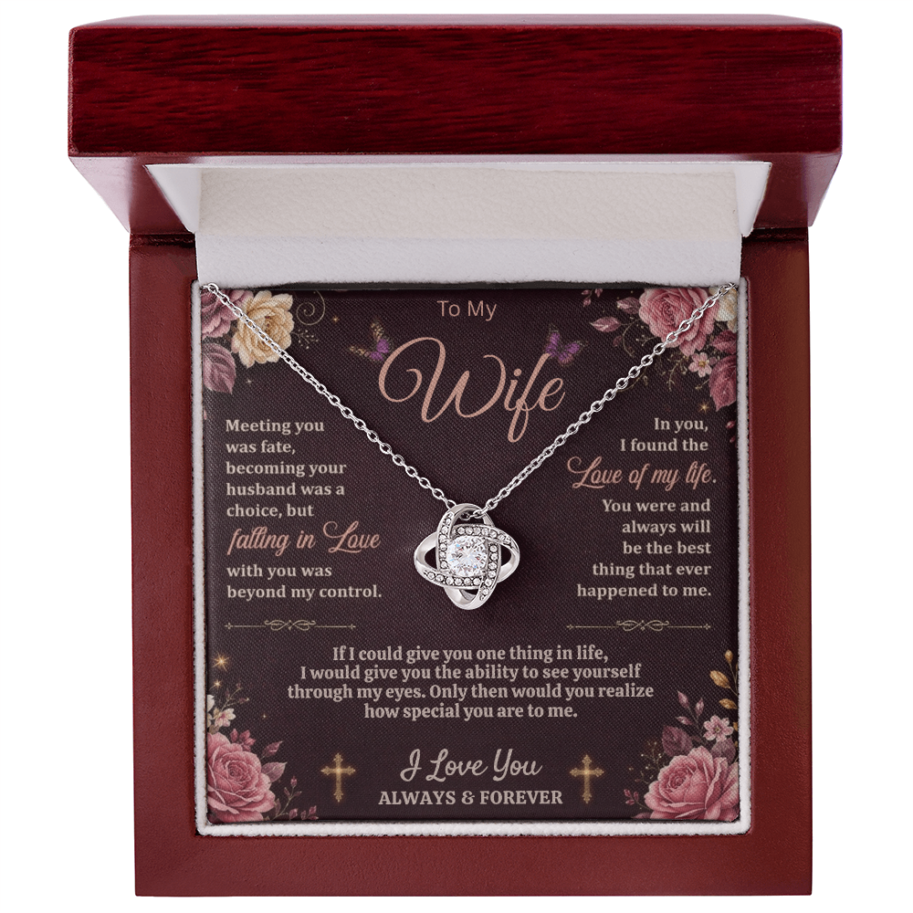 Silver-tone love-knot necklace and dark floral wife card in an open reddish-brown gift box on white.