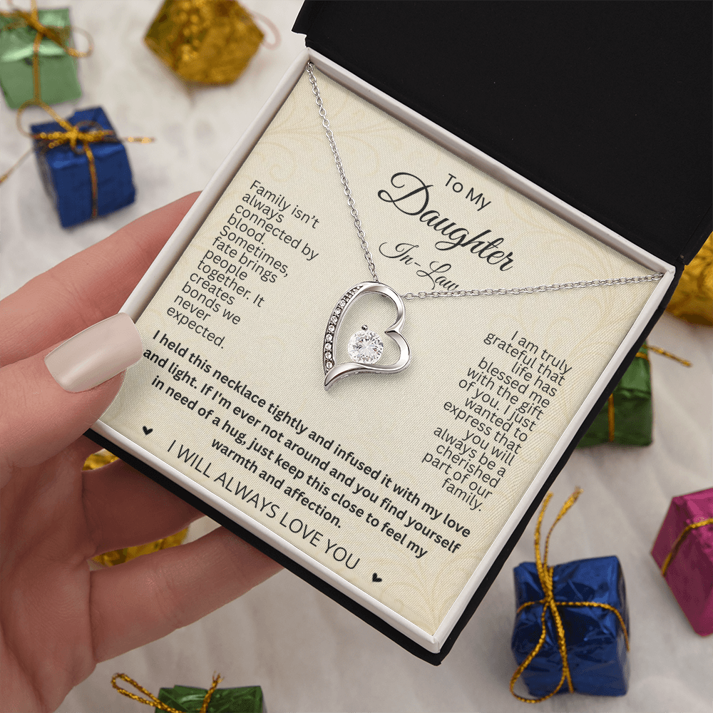 Hand holding a silver-tone heart necklace and daughter-in-law card in a black and white gift box above colorful miniature gifts.
