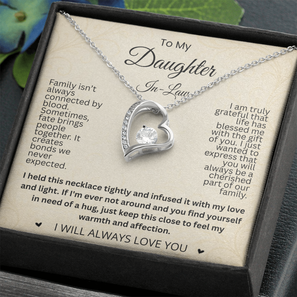 Silver-tone heart necklace and daughter-in-law card in a black gift box beside green leaves.